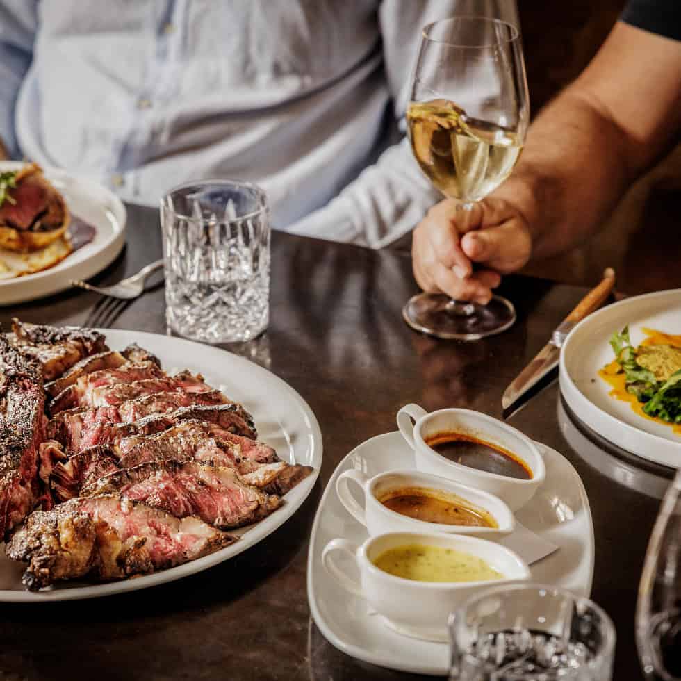 Group enjoying dinner with steak and wine at Kinsgleys